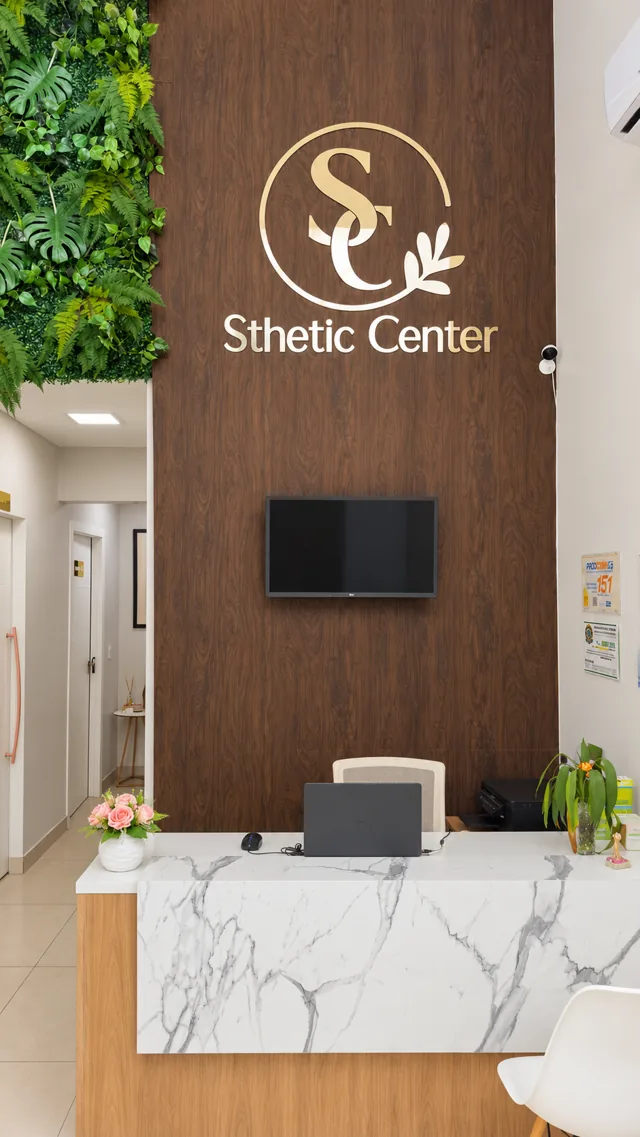 Recepção da Sthetic Center com balcão claro, painel de madeira e logo dourado